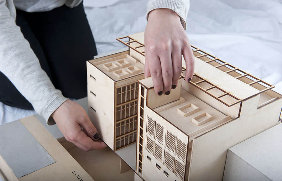 Building model — rear view with hands lifting roof section